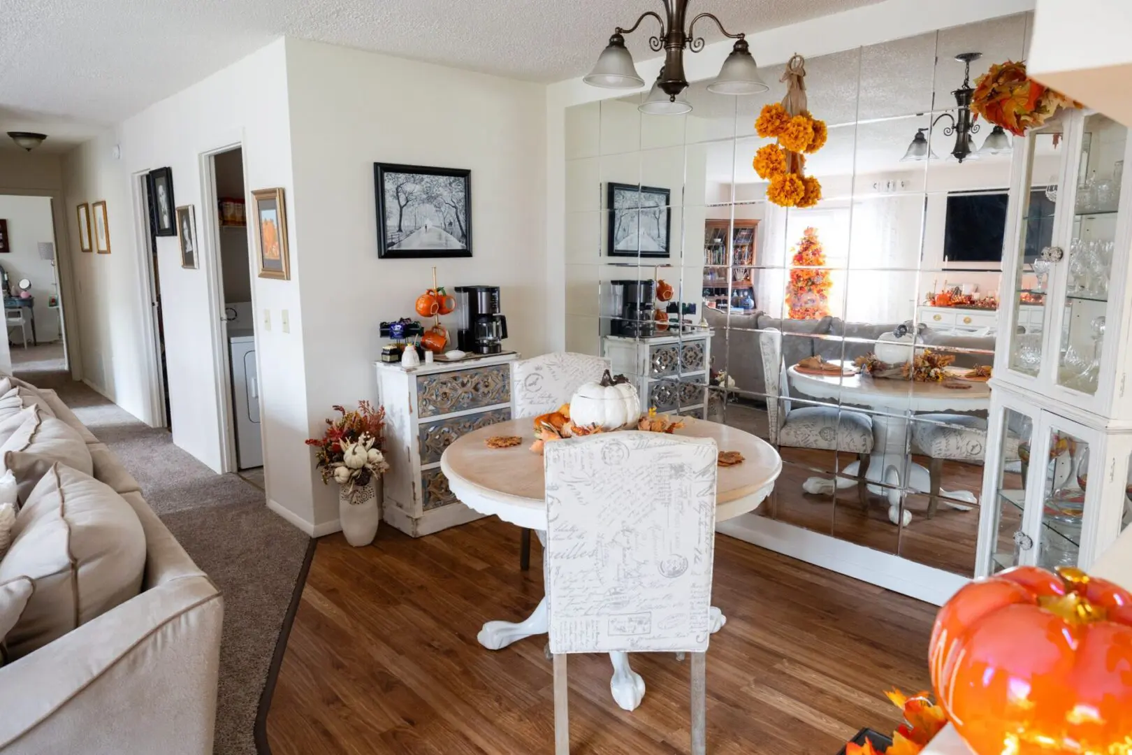 A dining room with white table and chairs, orange decorations.